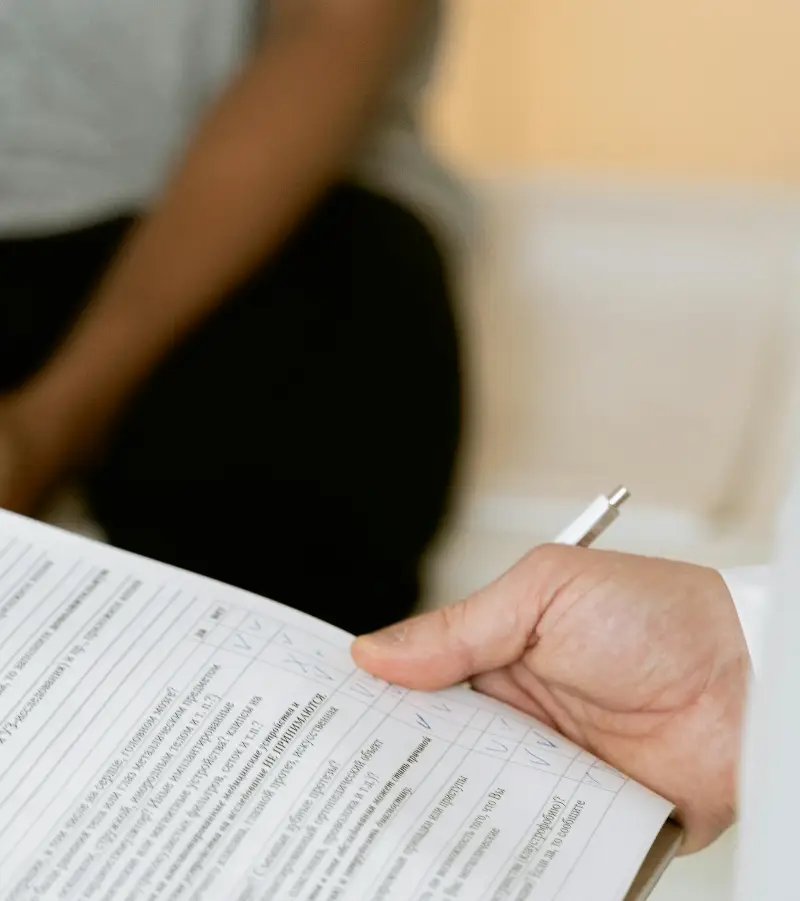A healthcare professional reviewing a patient's medical chart during a consultation.